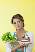 Frau hält zwei Teller in ihren Händen mit Kuchen und Salat