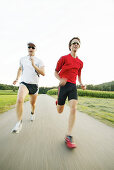 Two young men jogging on country road