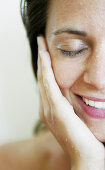 Woman holding her hand on cheek, waterdrops in face