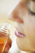 Young woman smelling bottle of perfumed body oil