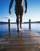 Man emerging from lake, walking on pier