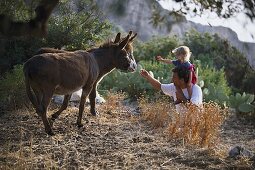Vater mit Tochter füttern Esel, Karpathos, Dodekanes, Griechenland