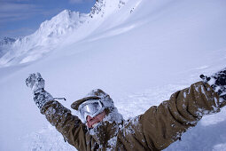 Mann schneebedeckt reißt die Arme in die Höhe, Kühtai, Tirol, Österreich
