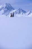 Two skier standing on snow hill, looking mountain panorama, Kuehtai, Tyrol, Austria