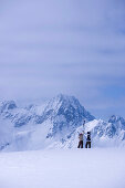 Two skier standing on snow hill, looking mountain panorama, Kuehtai, Tyrol, Austria