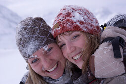 Two young women embracing together in snow, Kuehtai, Tyrol, Austria