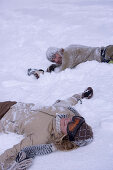 Junges Paar liegt im Schnee, Kühtai, Tirol, Österreich