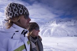 Young couple standing on slope, wearing sunglasses, Kuehtai, Tyrol, Austria