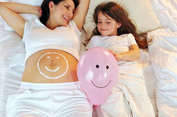 Schwangere Frau mit Smiley auf dem Bauch
