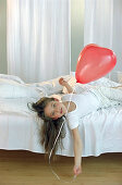 Mädchen spielt mit roten Luftballon
