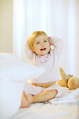 Toddler girl sitting on bed, Portrait