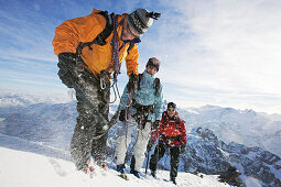 Ein Bergführer hackt mit einem Pickel Stufen aus dem Schnee für seine Kunden, einer Frau und einem Mann. Titlisgipfel, Zentralsschweiz, Schweiz, Alpen, Europa, MR