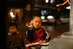 Shanghai,Old town, intersection, young boy doing homework under street lamp
