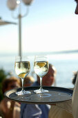 Waiter carrying two glasses of water in bar at lakefront, Leoni, Berg, Starnberger See, Bavaria, Germany