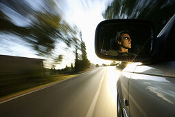 Man driving automobile, face in driving mirror, near Palafrugell, Costa Brava, Catalonia, Spain