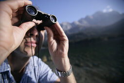Mann schaut durchs Fernglas, Eibsee, Zugspitze im Hintergrund, Bayern, Deutschland