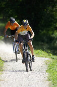 Two mountainbikers downhill on path with broken stones, Bavaria, Germany