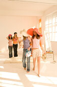 Vier weibliche Teenager (14-16) laufen umarmt im Zimmer, Modenschau