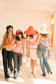 Vier weibliche Teenager (14-16) laufen umarmt im Zimmer, Modenschau