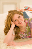 Teenage girl (14-16) lying on rug and smiling