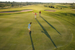 Golfers on golf course, long shadows, Apulia, Italy