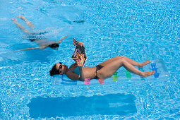 Frau liegt auf Luftmatratze, Mann taucht im Pool, Apulien, Italien