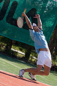 Male tennis player celebrating on court, arms outstretched, Apulia, Italy
