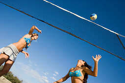 Two young woman playing beach volleyball, Apulia, Italy