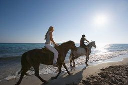 Young couple horseback riding at beach, Apulia, Italy