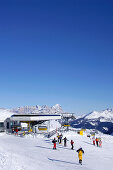Skiers at ski lift under blue sky, Passo Pordoi, Dolomites, Italy, Europe