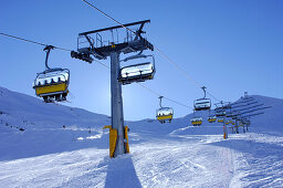 Skiers riding ski lift, Passo Pordoi, dolomites, italy