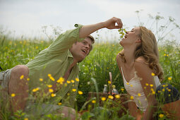 Couple having picnic on meadow, man feeding woman grapes