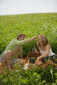 Couple having picnic on meadow, man feeding woman grapes
