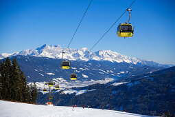 Achter Jet, 8-seated cabin cable car, Austria's 1st mono-cable aerial ropeway, skiers on slope, summit of the Dachsteinregion at horizon, Flachau, Salzburger Land, Austria