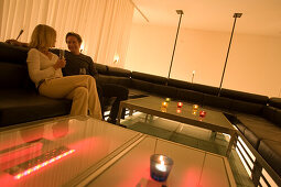 Couple sitting on lounge, tablet pc ins foreground, Vernissage Club, Design by Heinz Julen, Zermatt, Valais, Switzerland