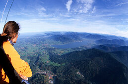 View from the basket of a hot air balloon to Gmund and lake Tegernsee with young woman in foreground, Bavarian alps, Upper Bavaria, Bavaria, Germany