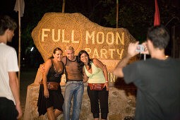Young people taking a picture in front of an stone with an inscription, Full Moon Party, Hat Rin Nok, Sunrise Beach, Ko Pha-Ngan, Thailand