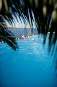 Woman in bikini leaning back in infinity pool, Porto Vecchio, Southern Corse