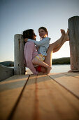 Mother and daughter sitting on jetty, Santa Giulia Beach, Southern Corse, France