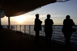 Menschen stehen bei Sonnenuntergang an der Reling, Kreuzfahrtschiff MS Delphin Renaissance