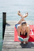 Bayern, Deutschland, Starnberg, Starnberger See, Frau lesend am See, Leoni, blond, lesen, Frau, Füße, Bikini, Wasser, See, rot