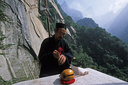 Einsiedler, Mönch, Hua Shan,Einsiedlermönch, Daoist im Gebet vor seiner kleinen Hütte in einer Steilwand, Huashan, Provinz Shaanxi, China, Asien