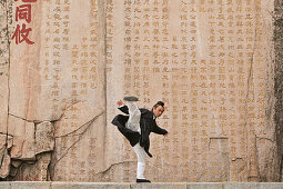 Taoistischer Mönch Zhang Qingren demonstriert die hohe Kunst des Taichi, 24-Figuren Zyklus vor berühmter Inschrift in Felswand, Gedicht des Tang Kaisers Li Longji, Xuanzong, Taishan, Provinz Shandong, UNESCO Weltkulturerbe, China, Asien