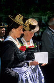 Two elderly women wearing dirndl dresses, reading the songs for the religious service, pilgrimage to Raiten, Schleching, Chiemgau, Upper Bavaria, Bavaria, Germany