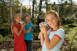Four girls playing with a tin can phone, children's birthday party
