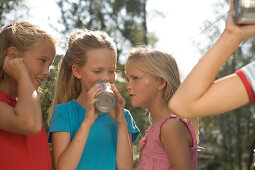 Four girls playing with a tin can phone, children's birthday party