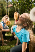 Girls playing donut catching, children's birthday party
