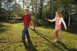 Ein Mädchen und ein Junge spielen Eierlaufen, Kindergeburtstag