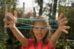 Girl playing cat's cradle, children's birthday party