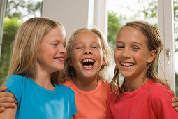 Three girls standing side by side and laughing, children's birthday party